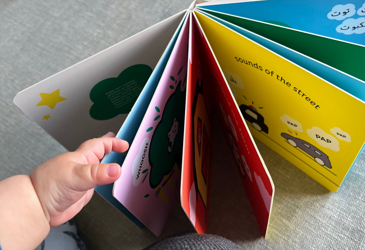 Child's hand holding a high contrast children's book open on a gray surface